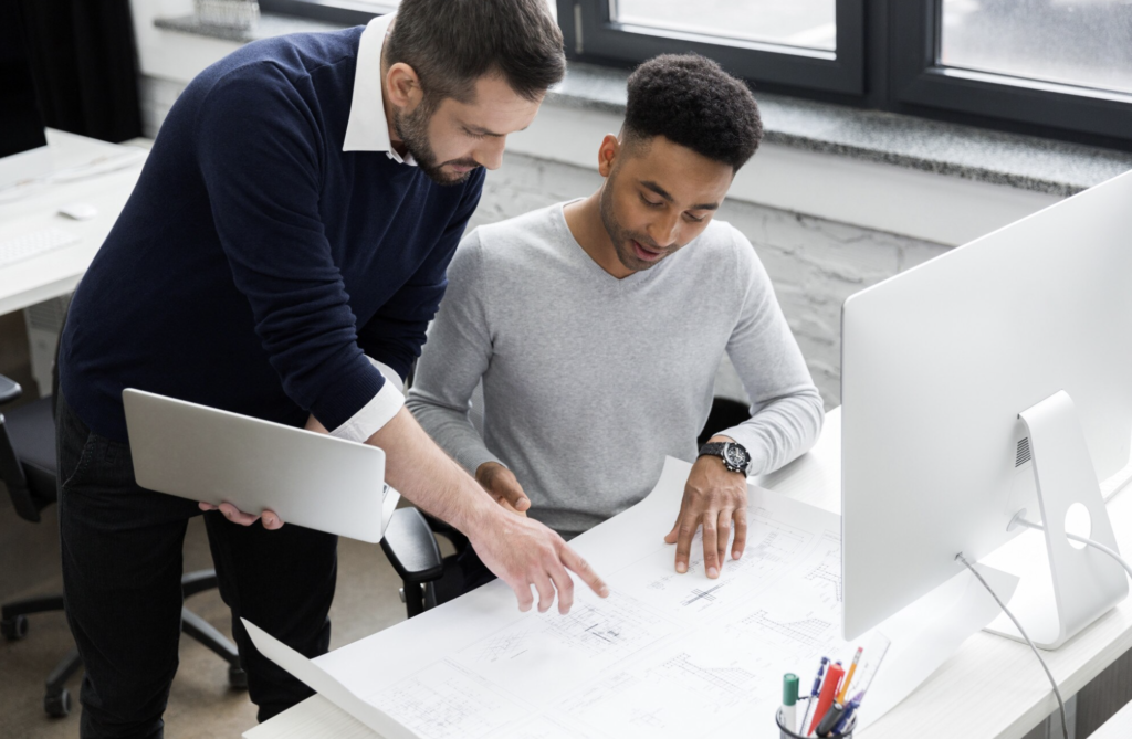 Conoce nuestra empresa. Dos ingenieros revisando un plano técnico en la mesa de trabajo